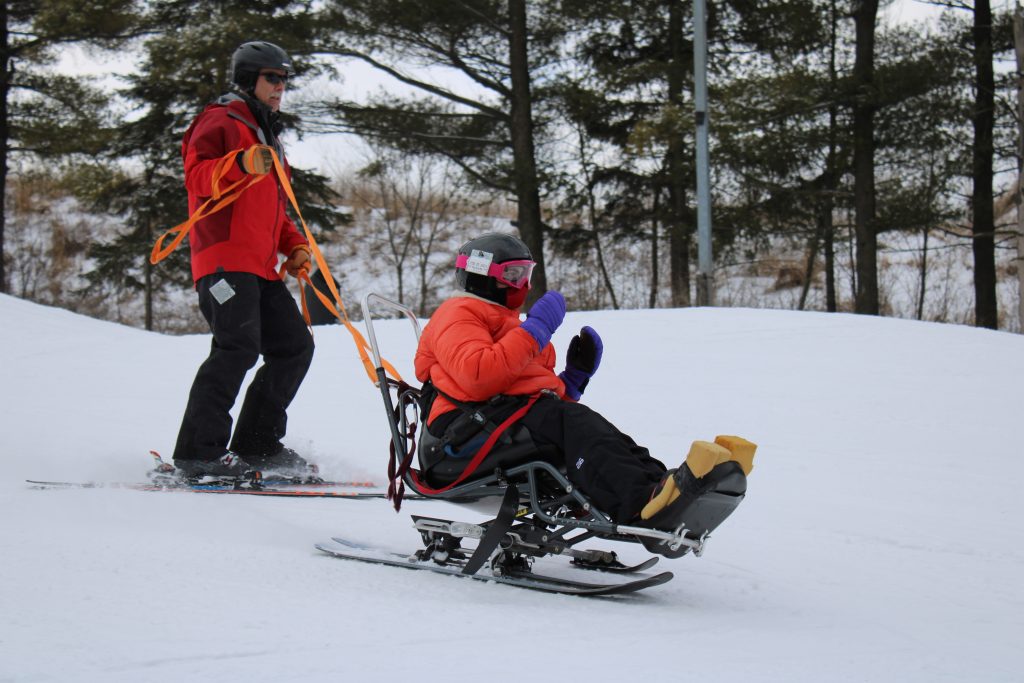 action photo of student bi-skiing with the assistance of an instructor