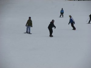 student snowboarding with volunteers following behind