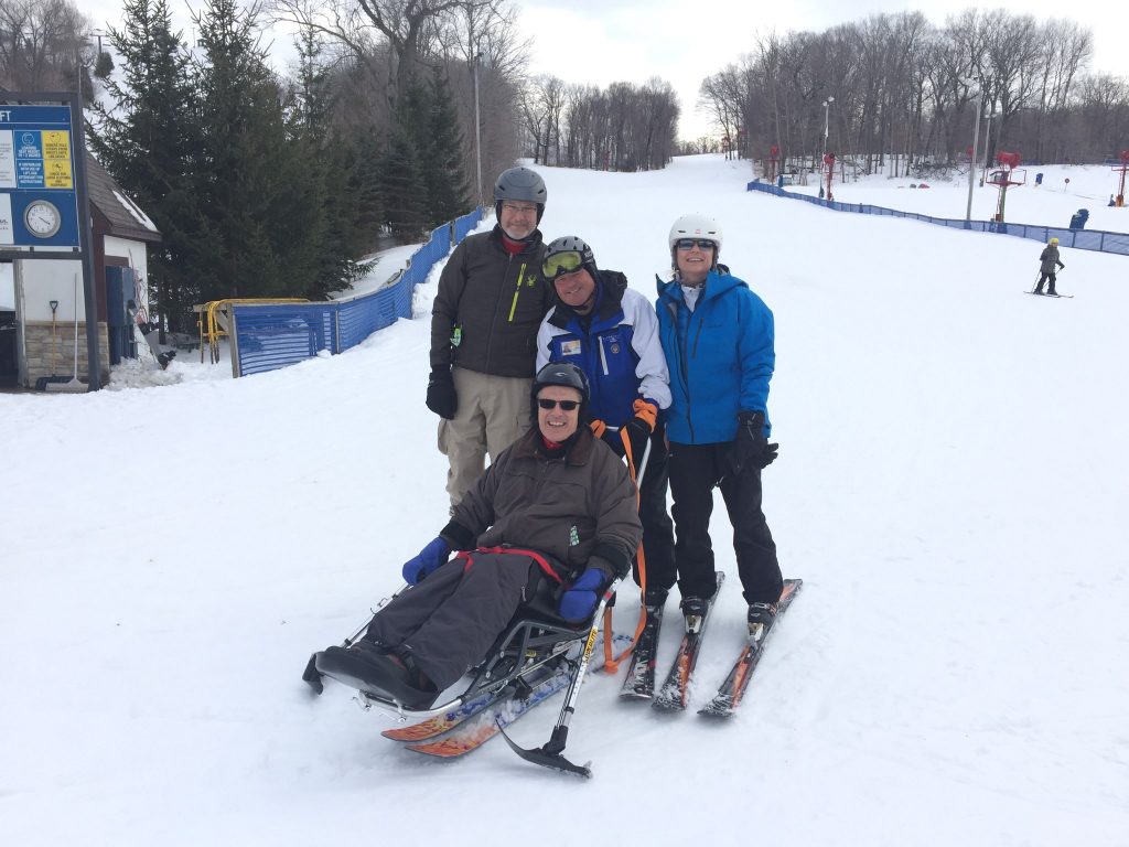 volunteers in group photo with adult bi-skier